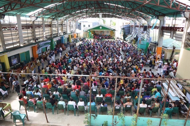 Recipients of Tzu Chi’s aid gather in a covered court.