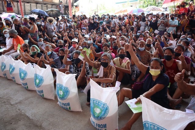 Cebu beneficiaries give their two thumbs up after claiming their 20-kg rice relief.