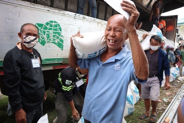 A man cheers in glee after receiving his rice relief.