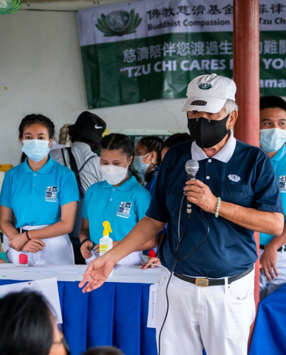 A Tzu Chi volunteer addresses beneficiaries while scholars look on.