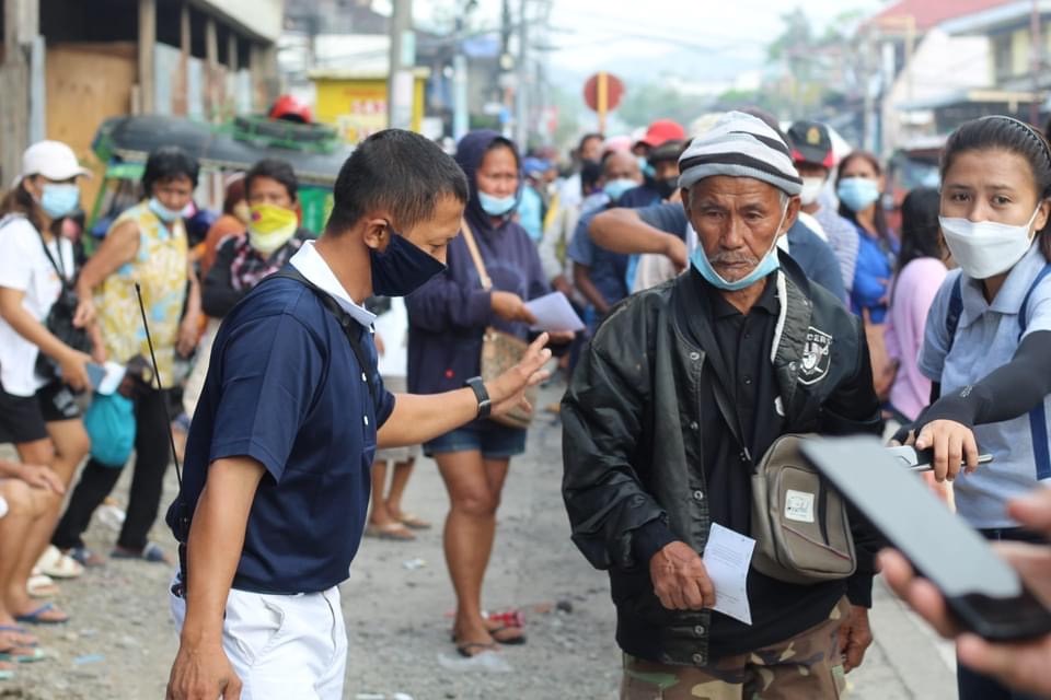 Volunteers guide a beneficiary after he claims his cash assistance.