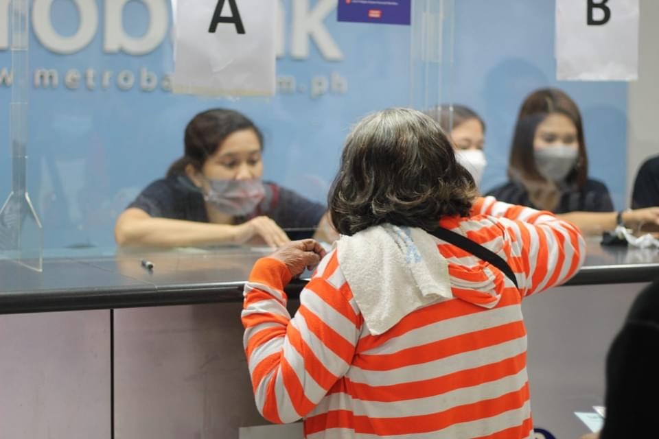A woman gives a Metrobank teller her information so she can claim her financial aid. 