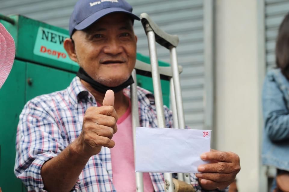 A beneficiary claims his P20,000 aid from Tzu Chi. The amount is given to families with five or more members.