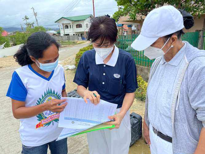 Carmen Calam (first from left), a barangay officer of Matabao, shows a list of residents to Tzu Chi volunteers. 【Photo by Marella Saldonido】