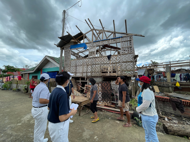 Maria Evelyn Socajel (in red cap), an officer from the Municipal Social Welfare and Development Office of the Municipality of Inabanga, Bohol, guides volunteers around the devastation in Barangay Lawis. 【Photo by Marella Saldonido】
