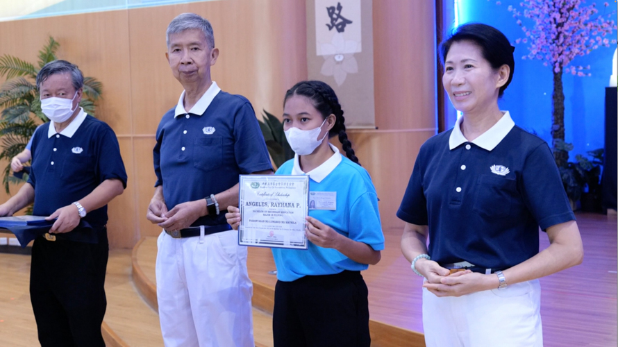 Rayhana Angeles (second from right) receives her scholarship certificate from Tzu Chi volunteers (from left) Johnny Kwok, Rudy Ong, and (first from right) Tzu Chi Philippines Deputy CEO Woon Ng. 【Photo by Jeaneal Dando】