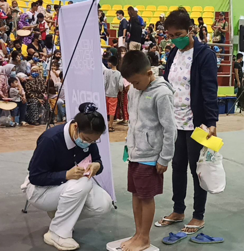 Tzu Chi volunteers help patients get their weight.【Photo by Matt Serrano】