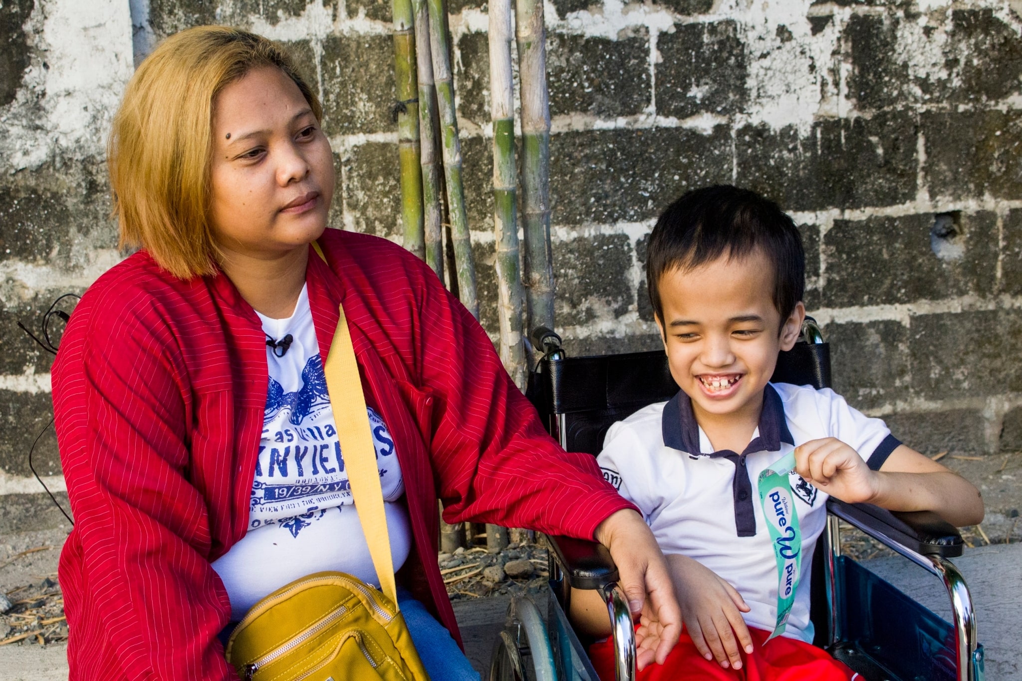 aneth de la Peňa (left) accompanies her son, 9-year-old Karl Olaso, to claim medical assistance benefits. Karl, a beneficiary for seven years, has congenital hydrocephalus and seizure disorder.【Photo by Matt Serrano】