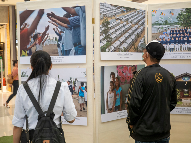 Shoppers stop to look at the pictures, recalling perhaps their own painful memories of the Category 5 storm.  【Photo by Matt Serrano】