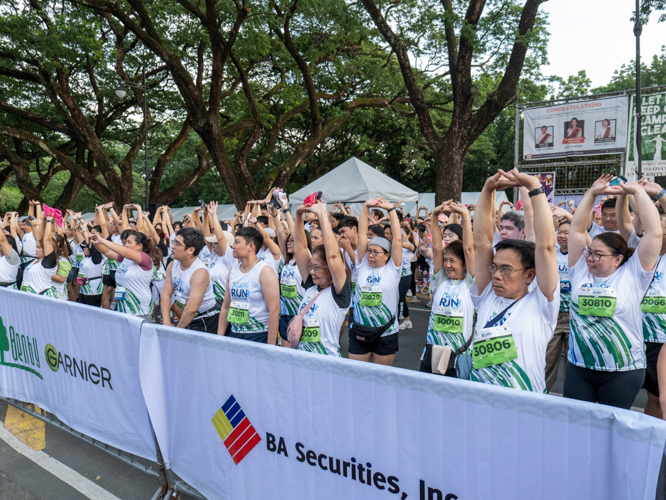 Runners warm up with stretches before the start of their respective race categories.