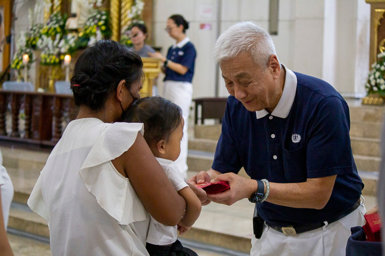 The parishioners receive a red envelope (angpao) blessed by Tzu Chi founder Dharma Master Cheng Yen. 【Photo by Marella Saldonido】