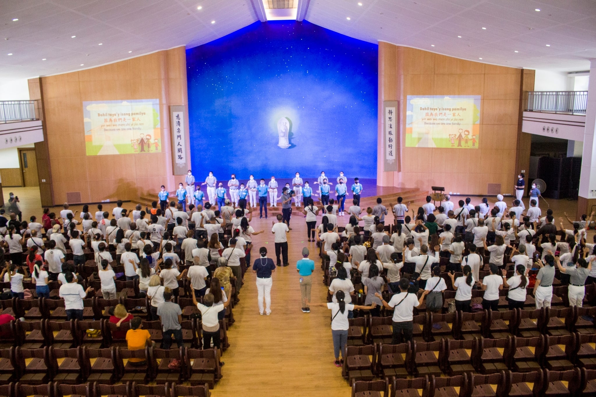 Tzu Chi volunteers and scholars lead the audience to a sign language performance of “One Family.”【Photo by Matt Serrano】