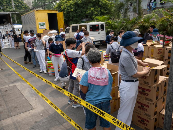 Fire beneficiaries follow an orderly line to receive their relief. 【Photo by Matt Serrano】