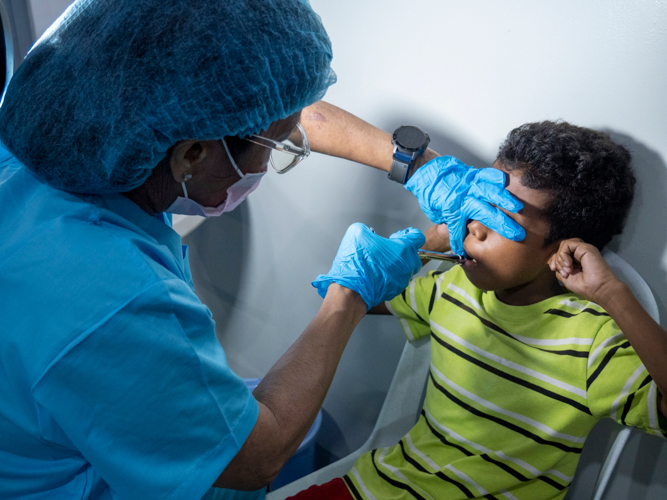 Rodnie Carpio pinches his ears as a volunteer dentist administers anesthesia before his extraction.