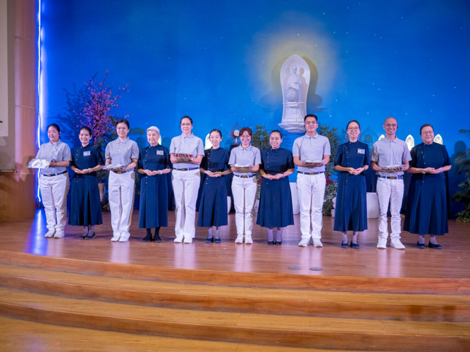At a moving-up ceremony for volunteers in training in March, Joy Gatdula (fifth from left) receives her uniform at the Jing Si Auditorium. 【Photo by Matt Serrano】