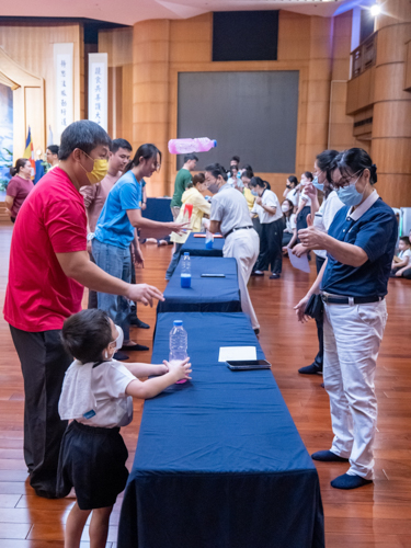 Families enthusiastically take part in the widely enjoyed bottle flip game, attempting to skillfully land partially-filled plastic bottles in an upright position. 【Photo by Marella Saldonido】