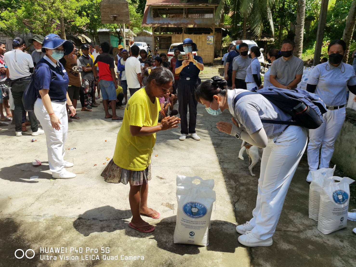 As a sign of respect and gratitude, volunteer bows as she gives two 10-kg sacks of rice to a beneficiary.