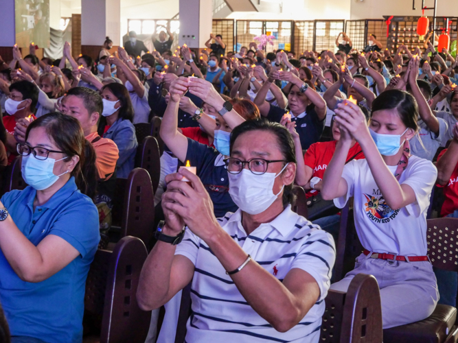 Guests raise their candles in prayer for peace at the ceremony’s culmination. 【Photo by Matt Serrano】