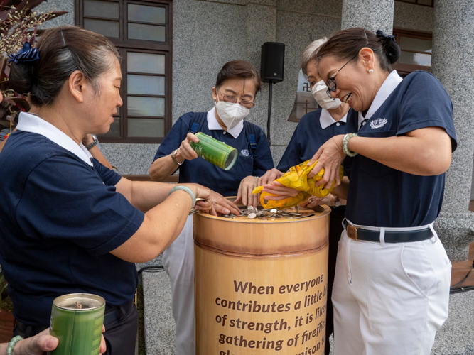 Volunteers pour in their donations into the big Tzu Chi coin bank. 【Photo by Matt Serrano】