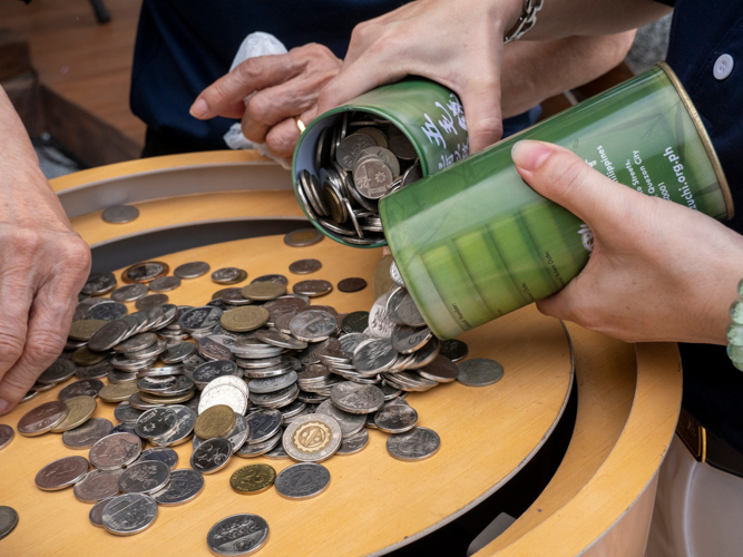 Volunteers pour in their donations into the big Tzu Chi coin bank. 【Photo by Matt Serrano】