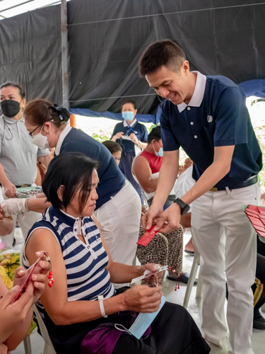 Tzu Chi Zamboanga volunteer Harvey Yap offers a patient a red angpao blessed by the Tzu Chi founder herself, Dharma Master Cheng Yen. 【Photo by Daniel Lazar】