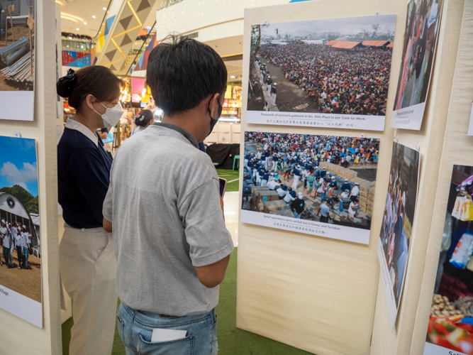 Shoppers stop to look at the pictures, recalling perhaps their own painful memories of the Category 5 storm.  【Photo by Matt Serrano】