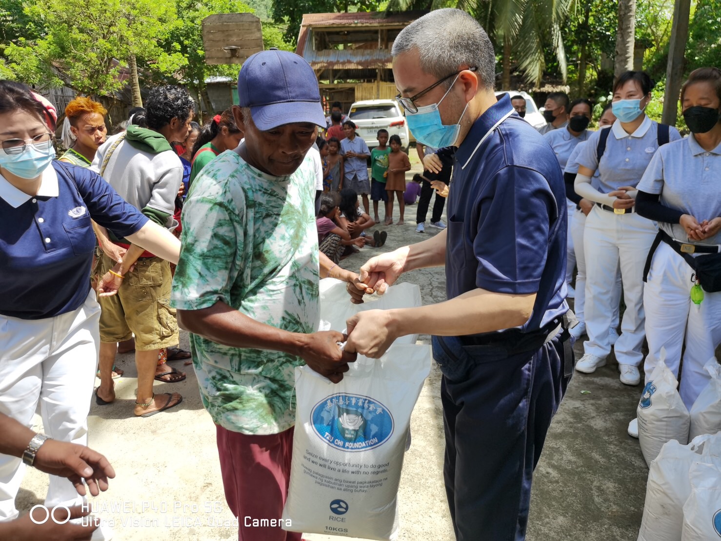 Volunteer hands out two 10-kg sacks of rice to a beneficiary.