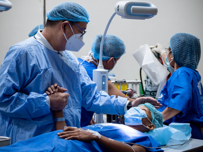 Dr. Anton Mari Lim, Tzu Chi Zamboanga Coordinator holds a teenage patient’s hand as he looks after him before his surgery. 【Photo by Daniel Lazar】