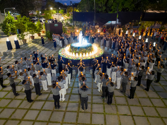 The ceremony concludes as attendees lift their lotus candles while singing a prayer for peace in the world.