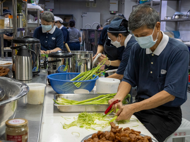 Volunteers tolerate the heat of a hot and crowded kitchen to prepare delicious vegetarian meals for guest.【Photo by Matt Serrano】