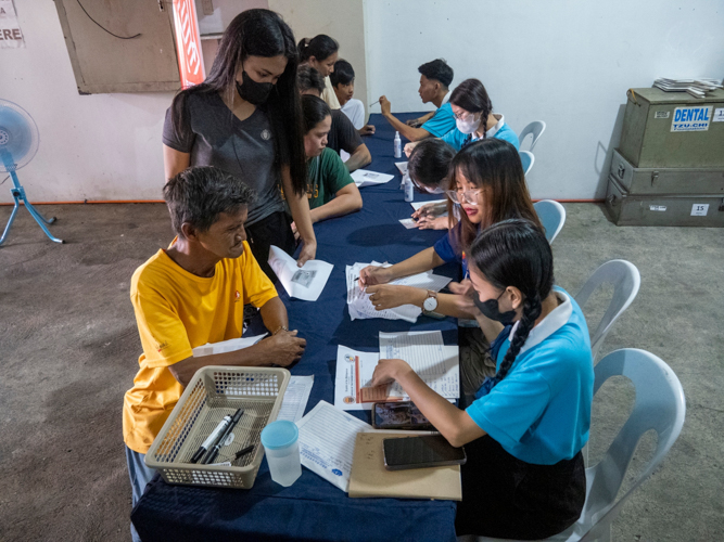Tzu Chi scholars assist patients in the registration area of the dental mission.