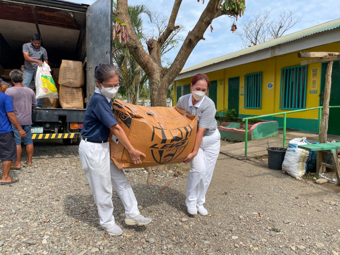 Volunteers unload boxes of school supplies to be distributed to Ibona Elementary School. 【Photo by Jeaneal Dando】