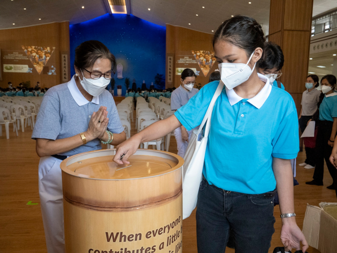 A scholar drops her pledge in a coin bank before leaving the Jing Si Hall. 【Photo by Matt Serrano】