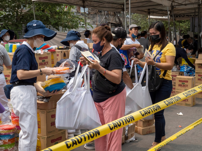 Fire beneficiaries open their eco bags to receive goods provided by Tzu Chi volunteers. 【Photo by Matt Serrano】
