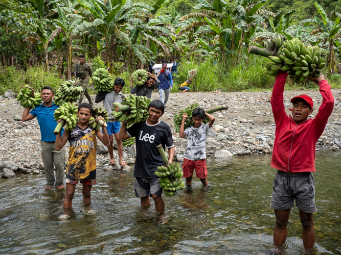 The Ata Manobo farmers excitedly transport their banana harvest by crossing a river on foot. 【Photo by Matt Serrano】