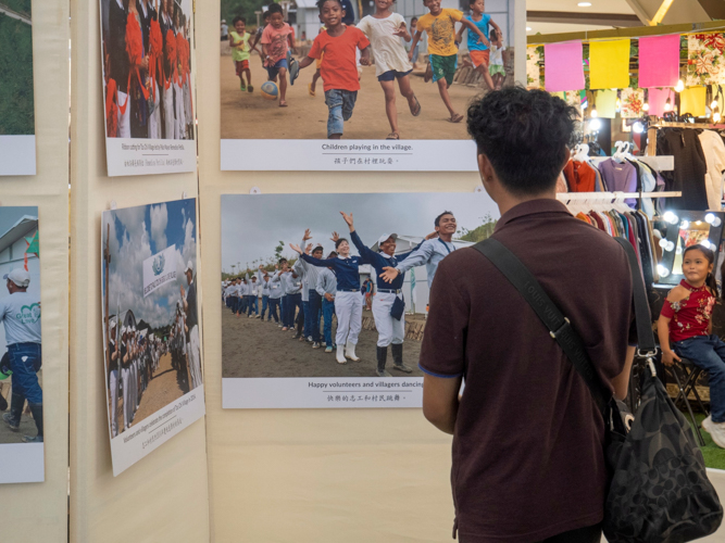 Shoppers stop to look at the pictures, recalling perhaps their own painful memories of the Category 5 storm.  【Photo by Matt Serrano】