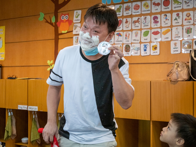 In the flour game, fathers attempt to find a hidden photo of their children in a plate full of flour using only their face. 【Photo by Harold Alzaga】