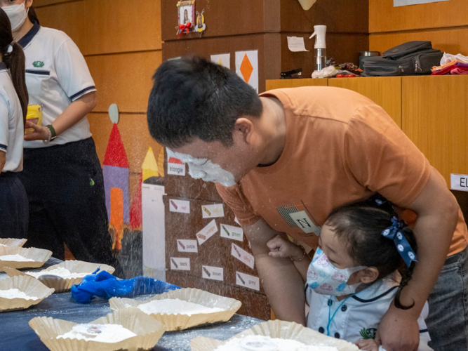 In the flour game, fathers attempt to find a hidden photo of their children in a plate full of flour using only their face. 【Photo by Harold Alzaga】