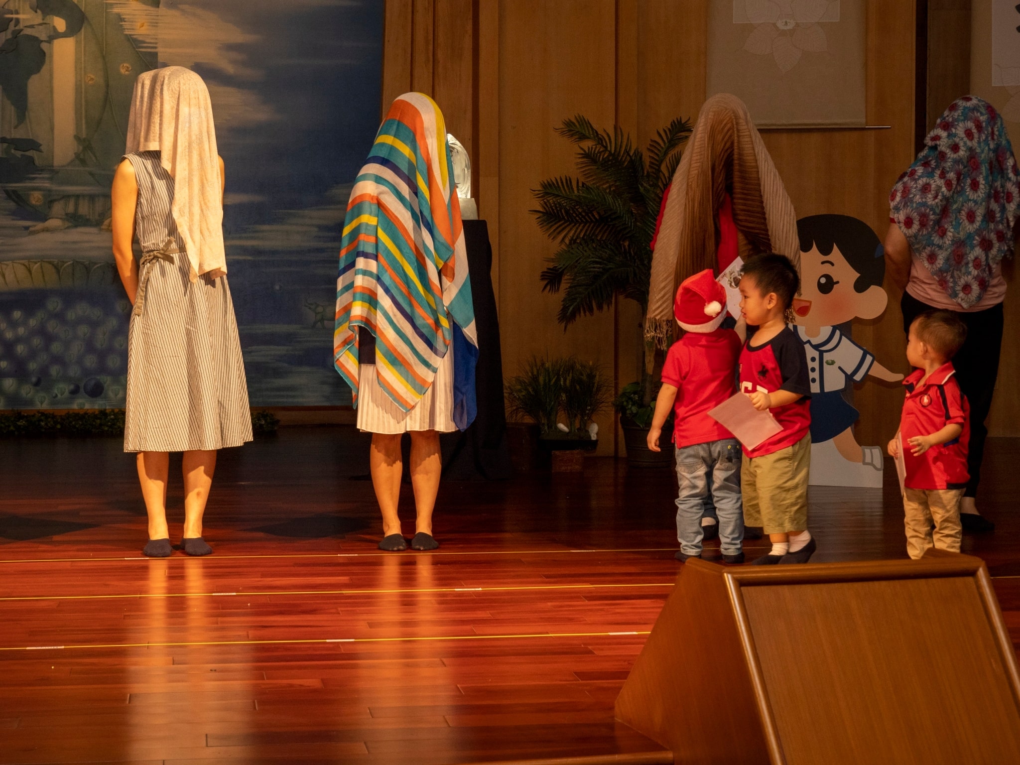 Covered with shawl, parents are identified by their children in a gift-giving game.【Photo by Harold Alzaga】