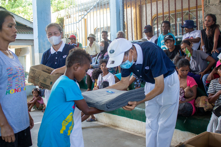 Tzu Chi volunteer Johnny Cheng bows in gratitude to a child as he hands him a blanket. 【Photo by Marella Saldonido】