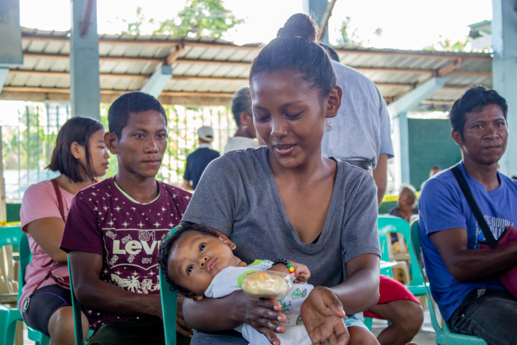 Mary Grace Piano arrives at the relief distribution site with her three-month old child. 【Photo by Marella Saldonido】