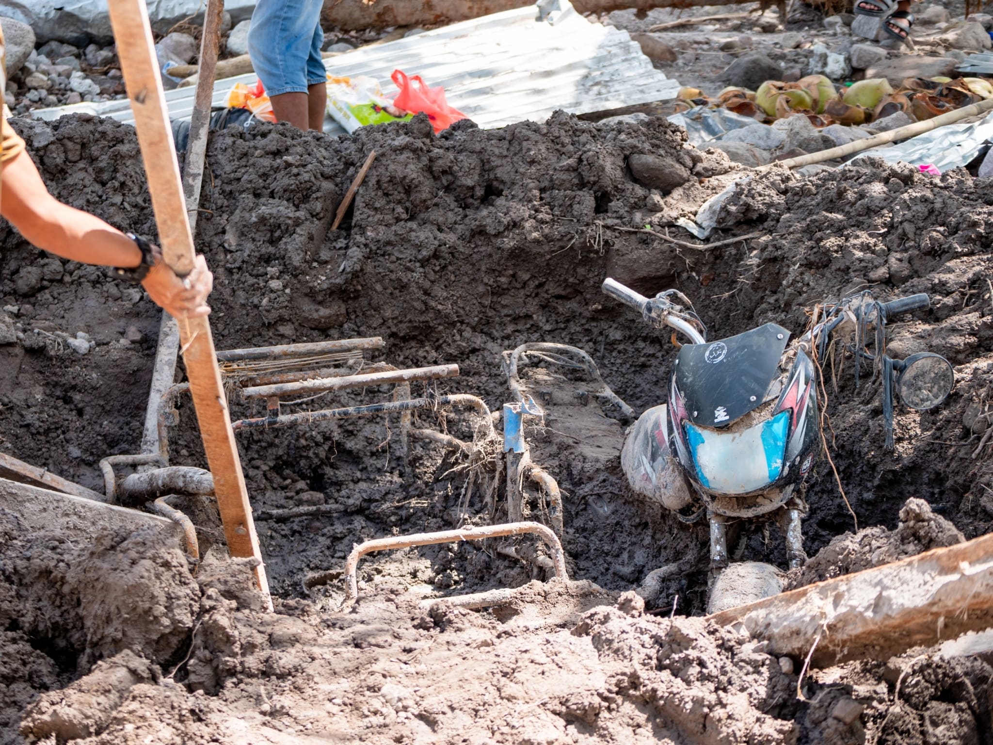 Residents try to rescue a motorcycle sidecar buried by mud. 【Photo by Daniel Lazar】