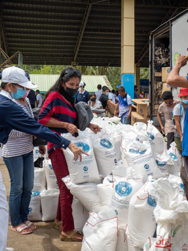 Myrna Sales receives rice from Tzu Chi while her son Edward gets Php 30,000 cash assistance. 【Photo by Jeaneal Dando】