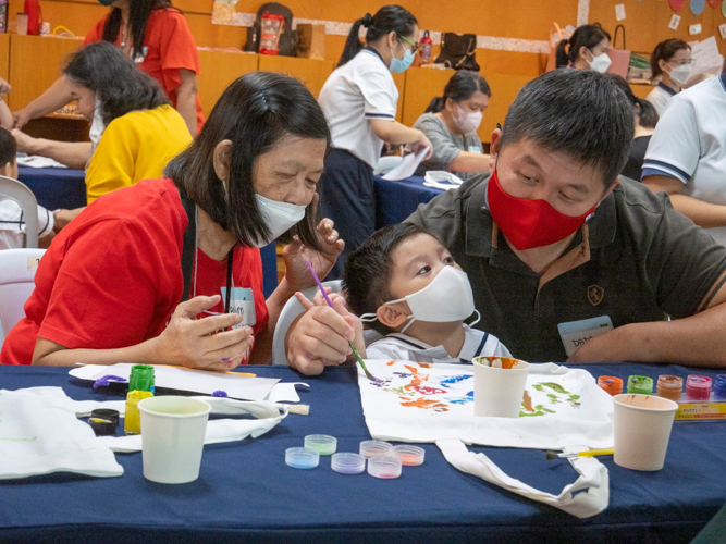 A student is guided by her grandmother and father during the painting activity. 【Photo by Matt Serrano】
