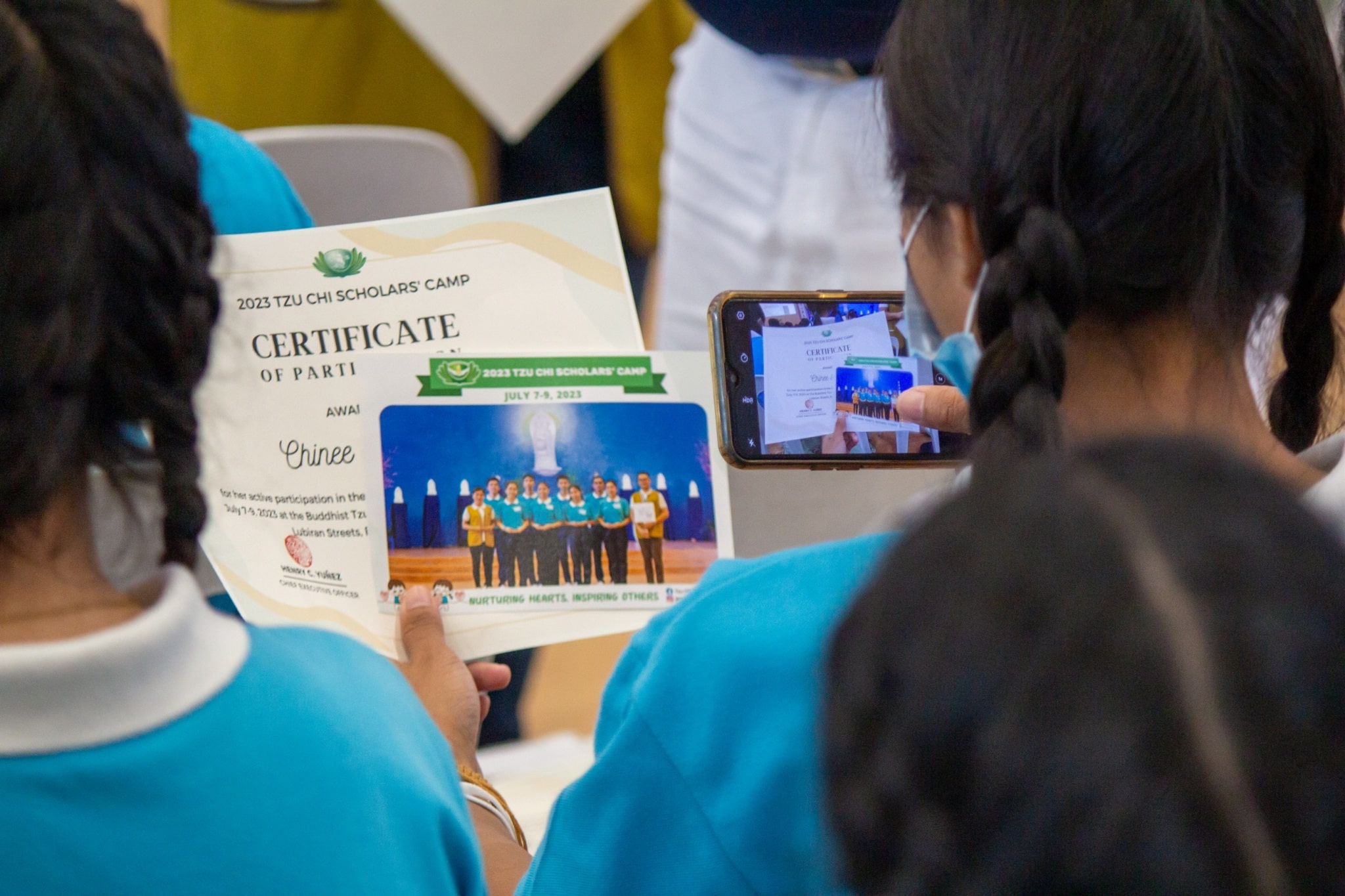 A scholar takes a photo of her camp souvenir and certificate. 【Photo by Marella Saldonido】