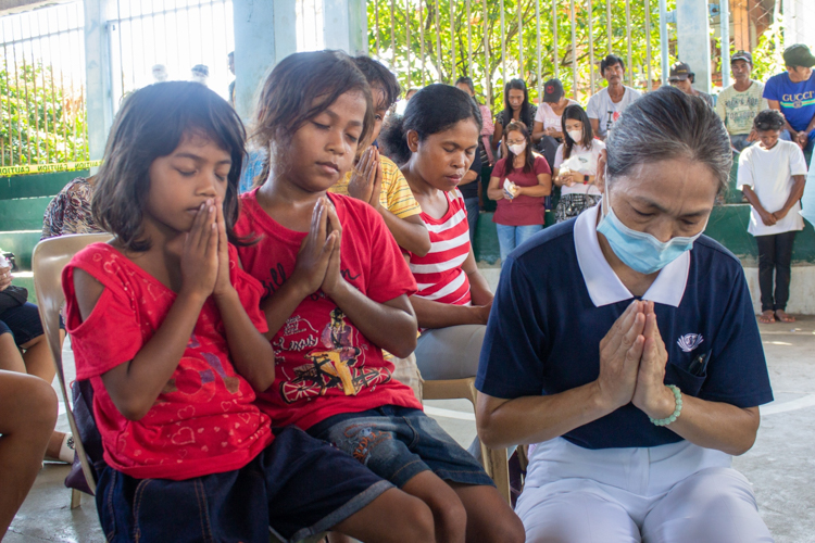 Volunteers lead beneficiaries in a solemn prayer. 【Photo by Marella Saldonido】