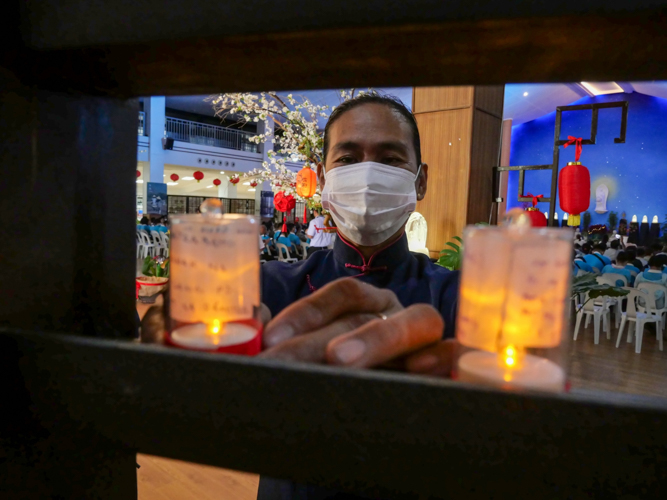 Guests write and wrap their prayers into a candle at the wishing wall. 【Photo by Matt Serrano】
