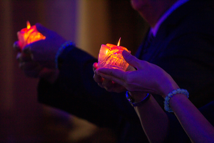 Volunteers and guests raise their candles as they sing a prayer for peace and harmony in the world. 【Photo by Marella Saldonido】