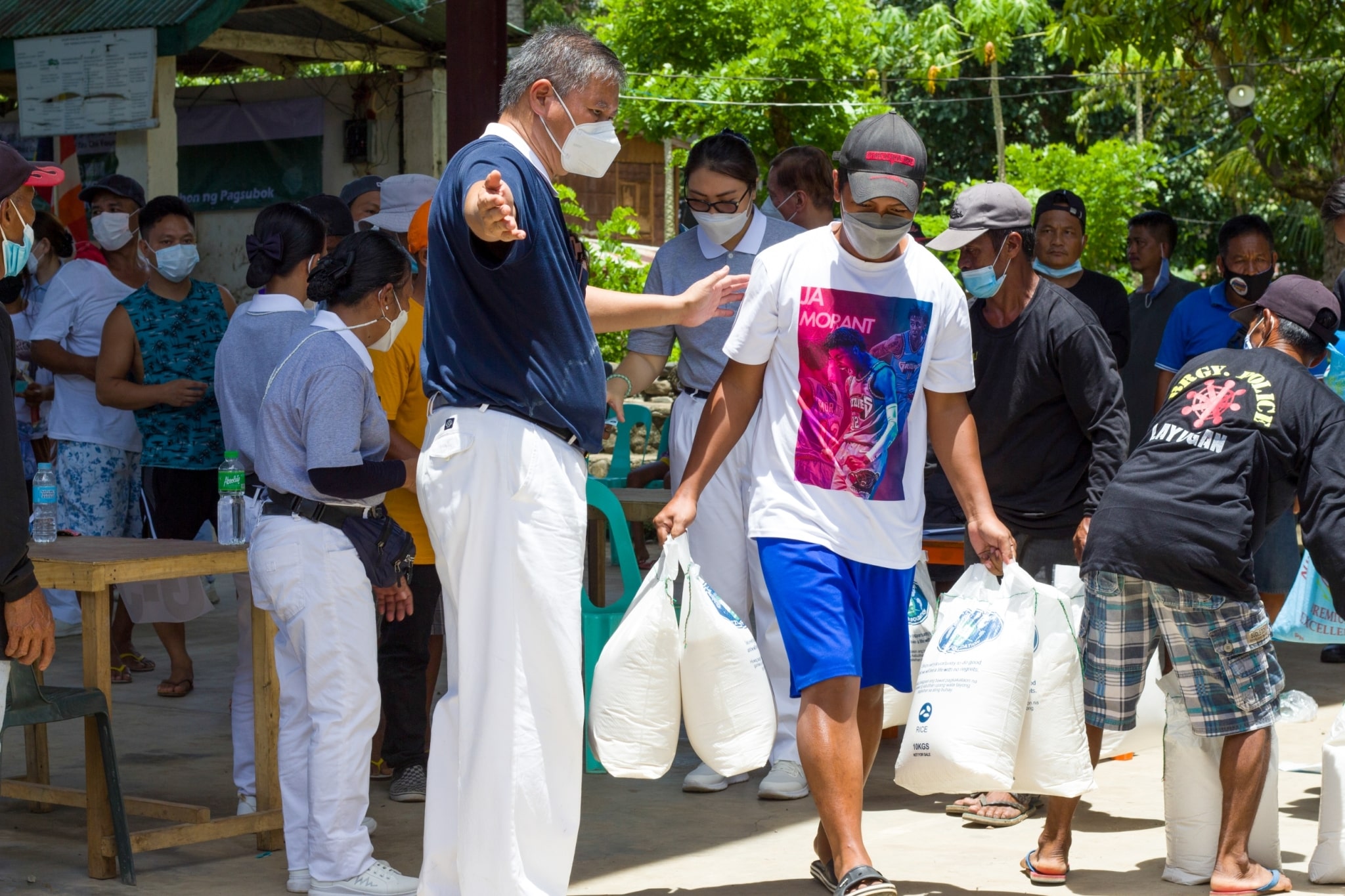 Volunteer Loreto Balete helps distribute rice to beneficiaries.【Photo by Matt Serrano】