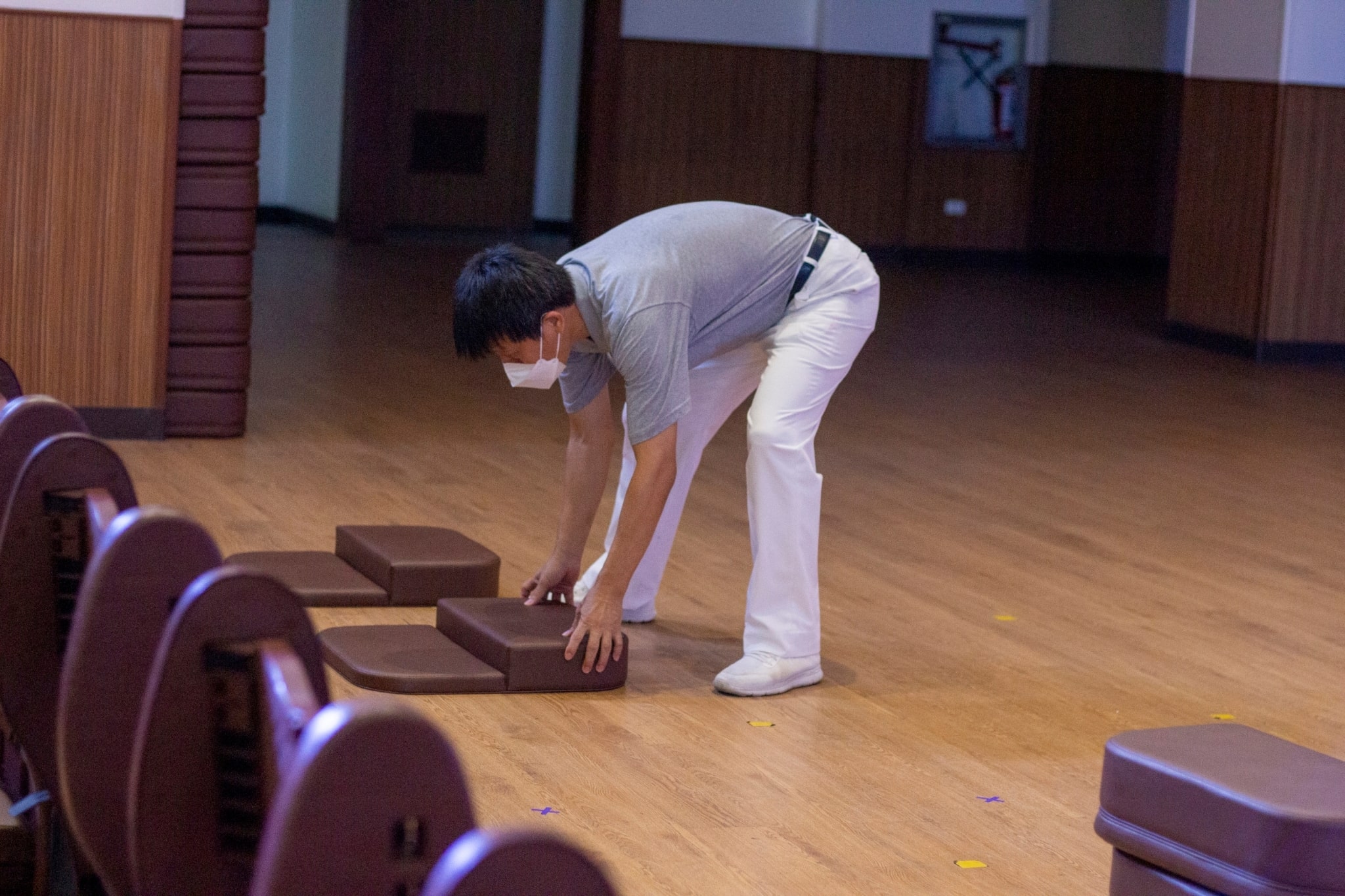 Ronald Lee aligns prayer kneeling pads inside the Jing Si Auditorium.【Photo by Matt Serrano】